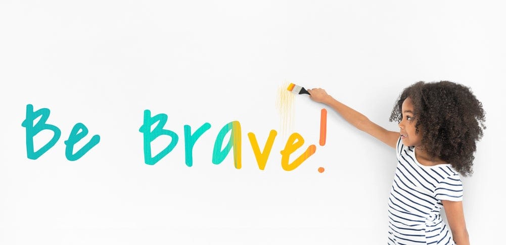 Young girl writing confidence quote "Be Brave"