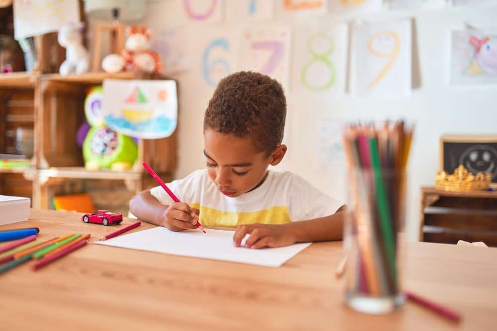 young boy coloring with colored pencils