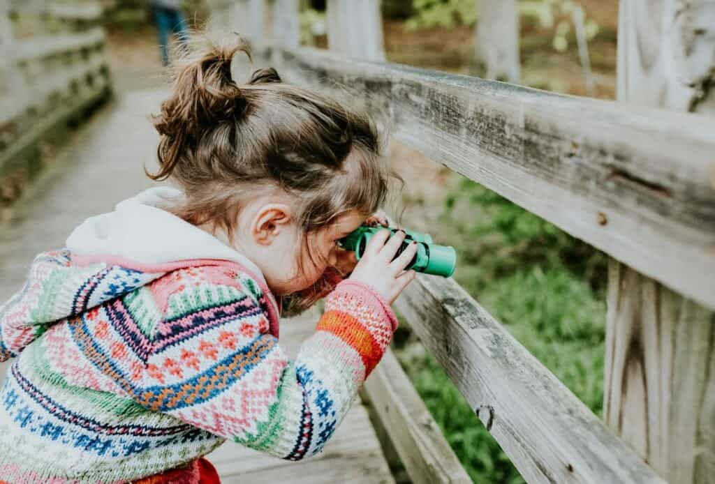 young girl using binoculars